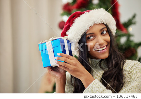 Christmas, curious or happy woman with a gift or box in present on a holiday celebration at home. Guessing, smile or excited Indian girl with present with giveaway prize package in a house in winter Christmas, curious or happy woman with a gift or box in present on a holiday celebration at home. Guessing, smile or excited Indian girl with present with giveaway prize package in a house in winter 136317463