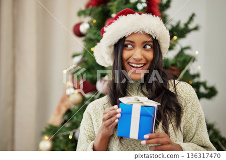 Christmas, thinking or happy woman with a gift or box in present on a holiday celebration at home. Wonder, smile or excited Indian girl with present with giveaway prize package in a house in winter Christmas, thinking or happy woman with a gift or box in present on a holiday celebration at home. Wonder, smile or excited Indian girl with present with giveaway prize package in a house in winter 136317470