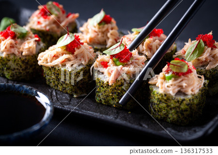 Japanese cuisine. Sushi rolls on a black platter 136317533