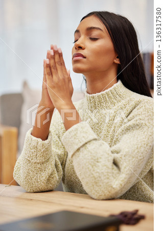Religion, prayer and young woman in her living room with christian faith, gratitude and worship. Spiritual, hope and religious female person praying with her hands together to god in her modern home. 136317580