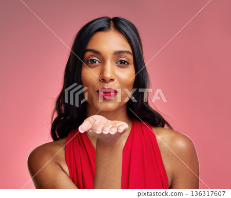 Woman, red lipstick and beauty, blow kiss with makeup and flirt, cosmetics and glow on pink background. Cosmetology, Indian female model pout with color in portrait and shine with wellness in studio 136317607