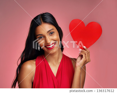 Portrait, heart and smile with a woman on a pink background in studio for love or romance. Valentines day, emoji and social media with a happy young female holding a shape or symbol of affection Portrait, heart and smile with a woman on a pink background in studio for love or romance. Valentines day, emoji and social media with a happy young female holding a shape or symbol of affection 136317612