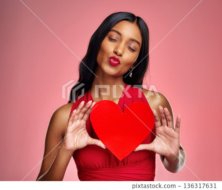 Kiss, heart and valentines day with a woman on a pink background in studio for love or romance. Red lips, emoji and social media with a happy young female holding a shape or symbol of affection 136317631