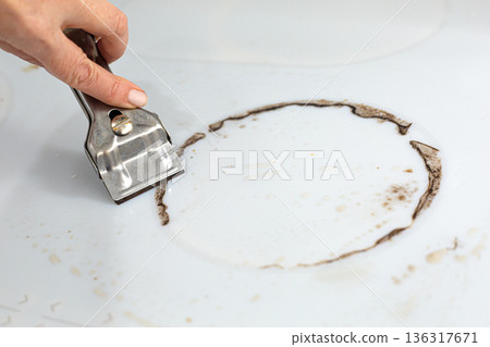 Woman cleaning electronic ceramic stove surface using special steel scraper Woman cleaning electronic ceramic stove surface using special steel scraper 136317671