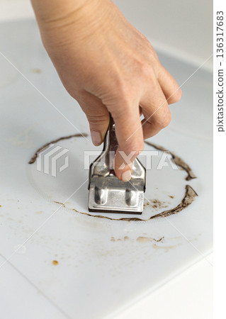 Woman cleaning electronic ceramic stove surface using special steel scraper Woman cleaning electronic ceramic stove surface using special steel scraper 136317683