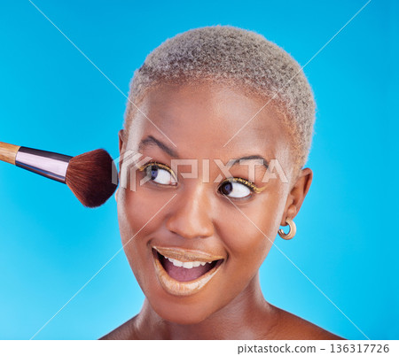 Black woman, face and brush of makeup in studio for application of foundation on blue background. Happy female model, wow and brushing beauty powder on skin with cosmetic tools for facial aesthetic Black woman, face and brush of makeup in studio for application of foundation on blue background. Happy female model, wow and brushing beauty powder on skin with cosmetic tools for facial aesthetic 136317726