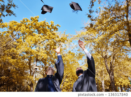 Graduation cap, students or friends and throw in air or sky for celebration, study success and achievement on campus. University people or graduate with college, school and education or scholarship 136317840