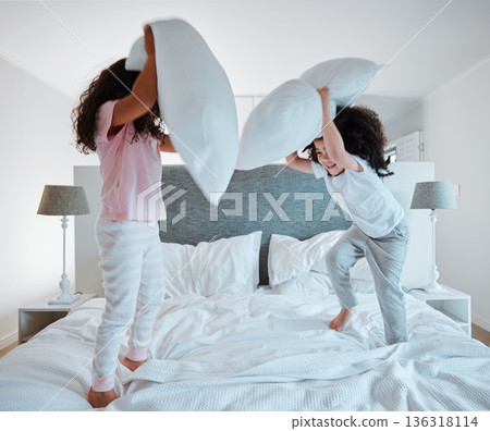 Happy siblings, pillow fight and playing on bed in morning together for fun bonding at home. Little girls, children or kids enjoying playful game, entertainment or fighting with pillows in bedroom Happy siblings, pillow fight and playing on bed in morning together for fun bonding at home. Little girls, children or kids enjoying playful game, entertainment or fighting with pillows in bedroom 136318114