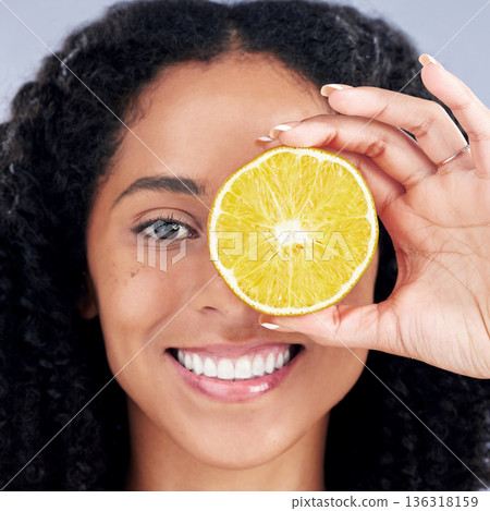 Portrait, wellness and woman with lemon eye for nutrition in closeup in grey studio background. Skincare, girl and vitamin c for facial treatment with natural organic food for dermatology or fruit. Portrait, wellness and woman with lemon eye for nutrition in closeup in grey studio background. Skincare, girl and vitamin c for facial treatment with natural organic food for dermatology or fruit. 136318159