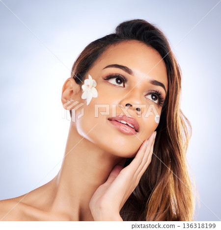 Woman, flower and cream on face in studio, thinking and beauty with wellness, makeup and aesthetic by background. Girl, model and plant for health, cosmetics and natural glow with ideas for skincare Woman, flower and cream on face in studio, thinking and beauty with wellness, makeup and aesthetic by background. Girl, model and plant for health, cosmetics and natural glow with ideas for skincare 136318199