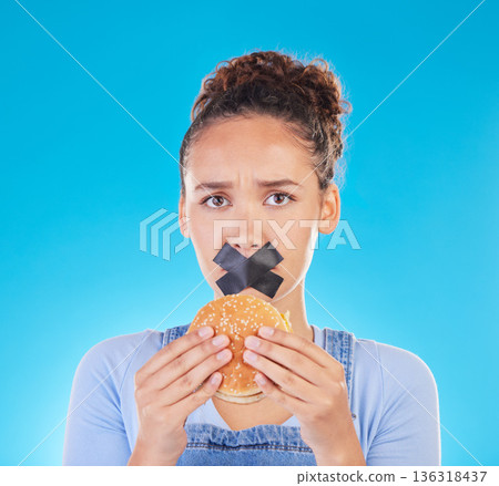 Burger, diet and woman reject fast food choice and unhappy gives bad, disgust and frustrated review for protection. Disaster, mistake and person disappointed isolated in a studio blue background 136318437