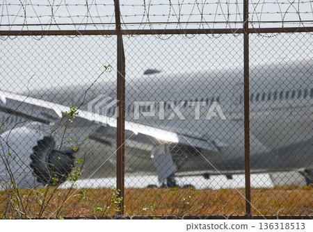 A huge passenger plane pulls onto the runway of Thailand airport, a view through the fence A huge passenger plane pulls onto the runway of Thailand airport, a view through the fence 136318513