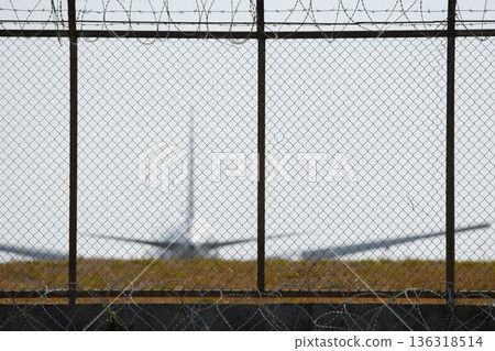 A huge passenger plane pulls onto the runway of Thailand airport, a view through the fence A huge passenger plane pulls onto the runway of Thailand airport, a view through the fence 136318514
