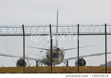 A huge passenger plane pulls onto the runway of Thailand airport, a view through the fence A huge passenger plane pulls onto the runway of Thailand airport, a view through the fence 136318516