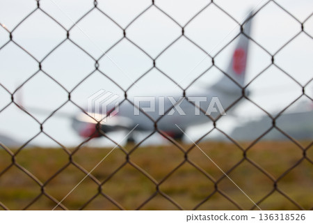 A huge passenger plane pulls onto the runway of Thailand airport, a view through the fence A huge passenger plane pulls onto the runway of Thailand airport, a view through the fence 136318526