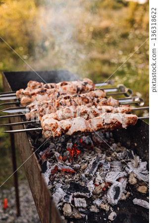 Pork shashlik on skewers grilling over hot charcoal outdoors, close up 136318622