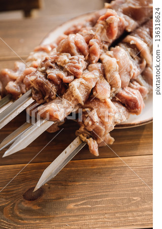 Raw marinated meat on metal skewers on wooden table, barbecue preparation closeup Raw marinated meat on metal skewers on wooden table, barbecue preparation closeup 136318624