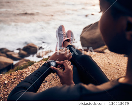 Relax, running and smart watch with hand of woman on rock for check, fitness tracker and heart rate. Workout, exercise and goal with closeup of female runner at beach for monitor, goals and time 136318679