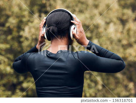 Fitness, back view of woman in woods and with headphones listening to music for workout. Exercise or committed, training or focused and female athlete listen to podcast for motivation in nature 136318701