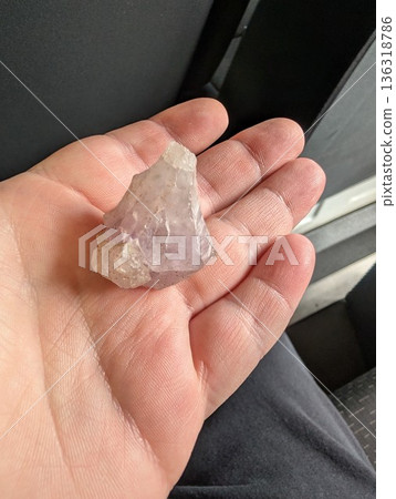 A man's hand holds a raw amethyst crystal, mineral mined at Wanda Mines in Argentina A man's hand holds a raw amethyst crystal, mineral mined at Wanda Mines in Argentina 136318786