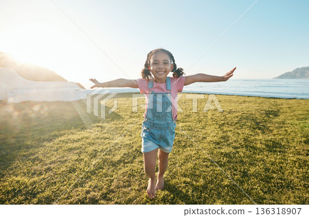 Happy, flying and portrait of girl in park with open arms excited with big smile, freedom and adventure. Childhood, happiness and young child running on grass for playing, relaxing and fun in nature 136318907