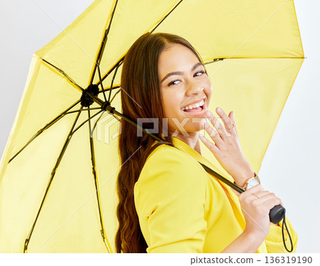 Portrait, yellow umbrella and life insurance with a woman in studio on a gray background blowing a kiss. Rain, winter fashion and smile with a happy young female model posing for cover or security 136319190