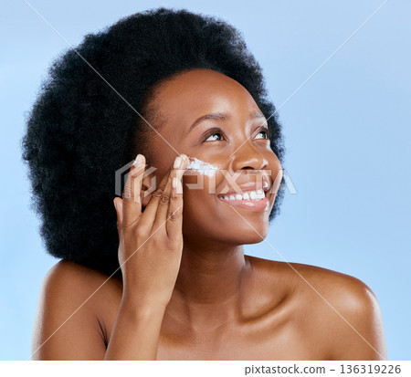 Black woman, face and cream, beauty and skincare with cosmetics on blue background. Moisturizer, lotion and product for skin with sunscreen and happiness, female model and dermatology in studio Black woman, face and cream, beauty and skincare with cosmetics on blue background. Moisturizer, lotion and product for skin with sunscreen and happiness, female model and dermatology in studio 136319226