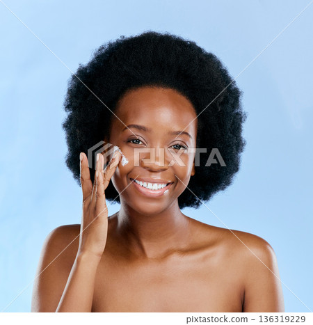 Black woman, portrait and cream, beauty and skincare with cosmetics on blue background. Moisturizer, lotion and product for skin with sunscreen and happiness, female model and dermatology in studio Black woman, portrait and cream, beauty and skincare with cosmetics on blue background. Moisturizer, lotion and product for skin with sunscreen and happiness, female model and dermatology in studio 136319229