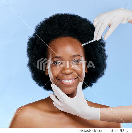 Black woman, face injection and beauty with cosmetic procedure, fillers and dermatology on blue background. Liquid collagen, facial and skincare with hands, female model and smile in portrait 136319232