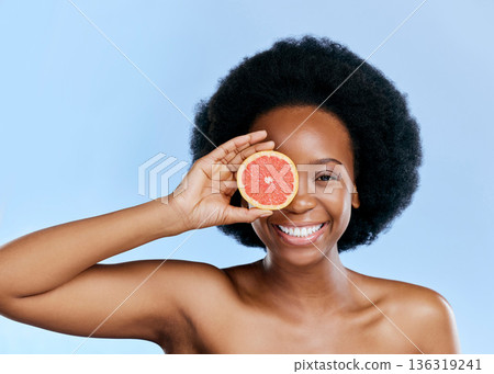 Black woman, smile in portrait with grapefruit and beauty, natural cosmetic treatment on blue background. Fruit, citrus and vitamin c, eco friendly skincare and happy female model with sustainability 136319241