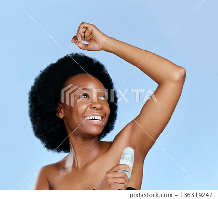 Happy, deodorant and armpit of black woman for wellness in studio isolated on a blue background. Smile, underarm and African model with roll on product for cosmetics, thinking and healthy fresh scent Happy, deodorant and armpit of black woman for wellness in studio isolated on a blue background. Smile, underarm and African model with roll on product for cosmetics, thinking and healthy fresh scent 136319242