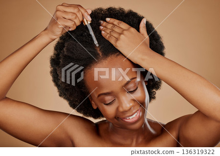 Oil serum, hair care or black woman with afro in studio on brown background for a healthy scalp. Smile, pipette or natural African girl at hairdresser salon for hairstyle treatment or beauty makeover 136319322