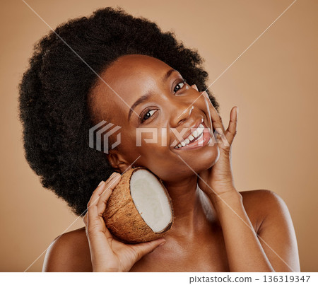Portrait, skincare and coconut with a model black woman in studio on a brown background for natural treatment. Beauty, skin and cosmetics with a happy young female person holding fruit for oil Portrait, skincare and coconut with a model black woman in studio on a brown background for natural treatment. Beauty, skin and cosmetics with a happy young female person holding fruit for oil 136319347