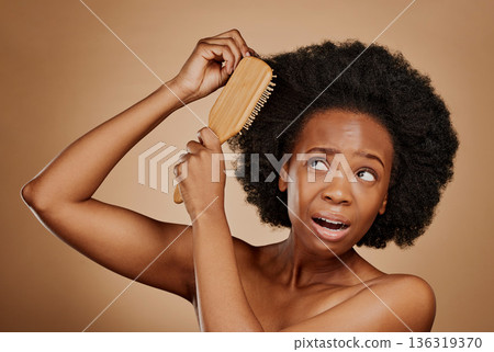 Black woman, problem and brushing hair in studio, brown background and tangled afro. Beauty, unhappy female model and comb knot in hairstyle with anxiety, pain and stress of damage to curly texture Black woman, problem and brushing hair in studio, brown background and tangled afro. Beauty, unhappy female model and comb knot in hairstyle with anxiety, pain and stress of damage to curly texture 136319370