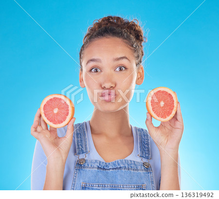 Portrait, kiss and woman with grapefruit in studio isolated on a blue background. Face, fruit and person with food for healthy diet, nutrition or wellness, eating and vitamin c, benefits and vegan. Portrait, kiss and woman with grapefruit in studio isolated on a blue background. Face, fruit and person with food for healthy diet, nutrition or wellness, eating and vitamin c, benefits and vegan. 136319492