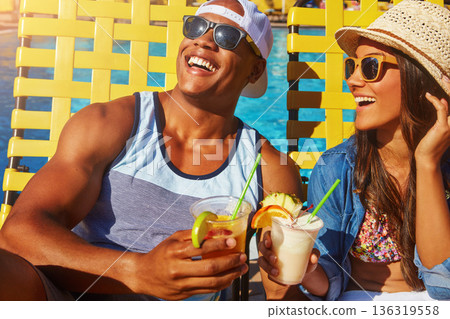 Couple, bonding and swimming pool with happiness and cocktails at resort for fun with sunshine. Drinks, summer and girl or boy at poolside for vacation to relax with smile or couple, tanning. 136319558