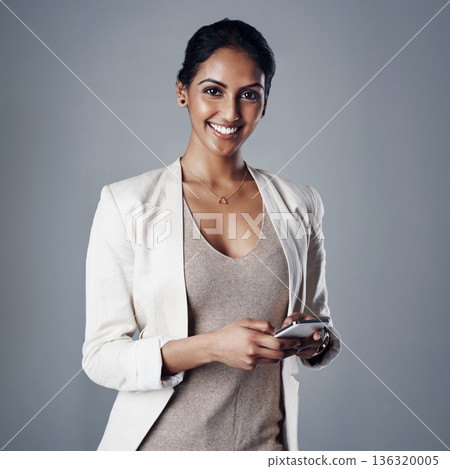 Technology, portrait of a woman with smartphone and against a studio background for social networking. Online communication, typing and Indian accountant person with cellphone pose for connectivity Technology, portrait of a woman with smartphone and against a studio background for social networking. Online communication, typing and Indian accountant person with cellphone pose for connectivity 136320005