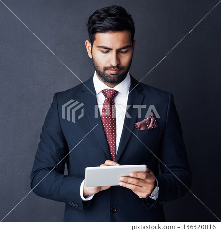 Serious, business man and tablet in studio, dark background and app for trading, planning or internet research. Corporate broker, indian male trader or focus on digital technology, online and website 136320016