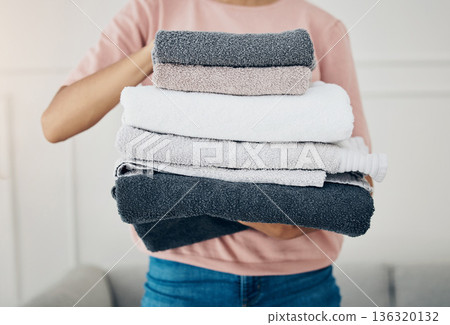 Towels, laundry and cleaning with a woman housekeeper closeup in the living room of a home for hygiene. Hands, housekeeping and chores with a female cleaner carrying a pile of washing in her house 136320132