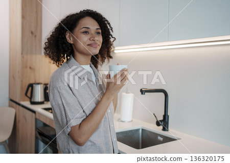 Contemplative Woman With Mug Before Kitchen, Serene Woman Studies Notes As Sunlight Gently Illuminates Contemplative Woman With Mug Before Kitchen, Serene Woman Studies Notes As Sunlight Gently Illuminates 136320175