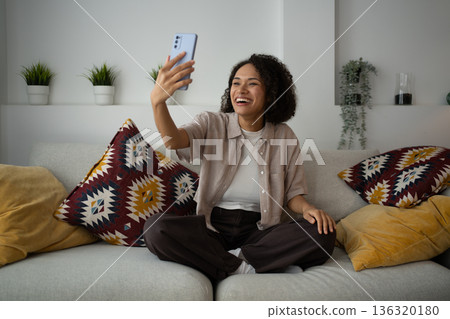 Relaxed Woman Takes Spontaneous Picture Indoors, Woman Smiles Naturally While Taking Casual Photo At Home Relaxed Woman Takes Spontaneous Picture Indoors, Woman Smiles Naturally While Taking Casual Photo At Home 136320180