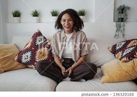 Happy Lady Relaxing, Cheerful Woman Sits Comfortably On Sofa Amid Lush Plants And Soft Pillows Happy Lady Relaxing, Cheerful Woman Sits Comfortably On Sofa Amid Lush Plants And Soft Pillows 136320188