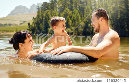 Family, child floating in tube with parents and swimming in lake with happiness in nature on summer vacation. Energy, adventure and fun outdoor, people in water with laughter, travel and holiday Family, child floating in tube with parents and swimming in lake with happiness in nature on summer vacation. Energy, adventure and fun outdoor, people in water with laughter, travel and holiday 136320445