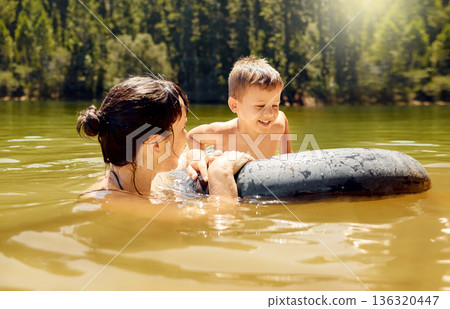 Travel, float and mother with her child in lake swimming while on a summer vacation or adventure. Happy, tubing and young mom bonding with boy kid in outdoor pond on tropical weekend trip or holiday. Travel, float and mother with her child in lake swimming while on a summer vacation or adventure. Happy, tubing and young mom bonding with boy kid in outdoor pond on tropical weekend trip or holiday. 136320447