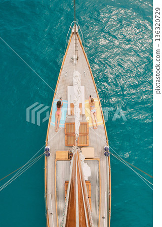 Aerial, ocean and women with phone on boat relax for cruise, luxury sailing and transport on sea. Social media, travel and female people on yacht for tropical journey, sunbathing and tourism on water Aerial, ocean and women with phone on boat relax for cruise, luxury sailing and transport on sea. Social media, travel and female people on yacht for tropical journey, sunbathing and tourism on water 136320729