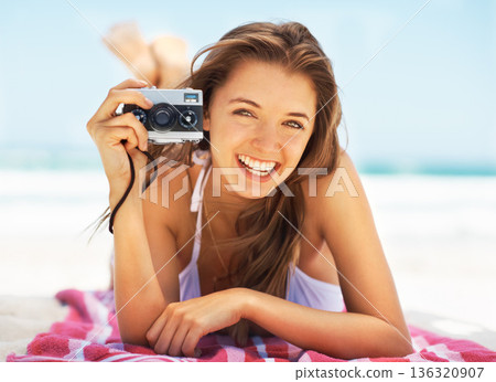 Portrait, camera and a woman tourist on the beach during summer for a holiday or luxury vacation. Ocean, bikini and smile with a happy young female photographer on the sand to relax by a coastal sea Portrait, camera and a woman tourist on the beach during summer for a holiday or luxury vacation. Ocean, bikini and smile with a happy young female photographer on the sand to relax by a coastal sea 136320907