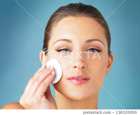 Skincare, portrait and woman with cotton pad on face, cosmetics and cleaning product for makeup. Dermatology, skin care and wellness for model with beauty, detox and facial glow on blue background. Skincare, portrait and woman with cotton pad on face, cosmetics and cleaning product for makeup. Dermatology, skin care and wellness for model with beauty, detox and facial glow on blue background. 136320950