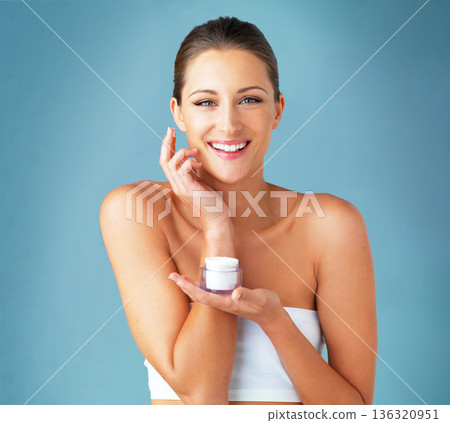 Skincare, cosmetics and portrait of happy woman with cream, dermatology and product on blue background. Lotion, skin care and wellness, model with smile, beauty treatment and facial glow in studio. Skincare, cosmetics and portrait of happy woman with cream, dermatology and product on blue background. Lotion, skin care and wellness, model with smile, beauty treatment and facial glow in studio. 136320951