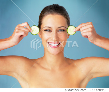 Skincare, cosmetics and cucumber, portrait of happy woman for dermatology and makeup on blue background. Happiness, natural skin care and wellness, face of model with beauty and facial glow in studio Skincare, cosmetics and cucumber, portrait of happy woman for dermatology and makeup on blue background. Happiness, natural skin care and wellness, face of model with beauty and facial glow in studio 136320959