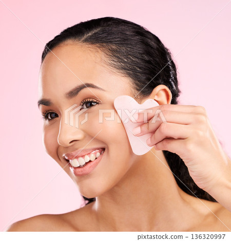 Facial massage, natural beauty and woman with a gua sha, skin glow and cosmetics. Face of a young aesthetic female model happy with self care and dermatology stone results on a pink background Facial massage, natural beauty and woman with a gua sha, skin glow and cosmetics. Face of a young aesthetic female model happy with self care and dermatology stone results on a pink background 136320997